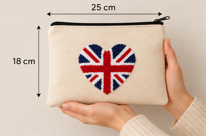 A beige fabric zip pouch with a heart-shaped Union Jack design on the front, held by two hands against a light beige background. Black dimension arrows and text indicate a width of 25 cm and a height of 18 cm.