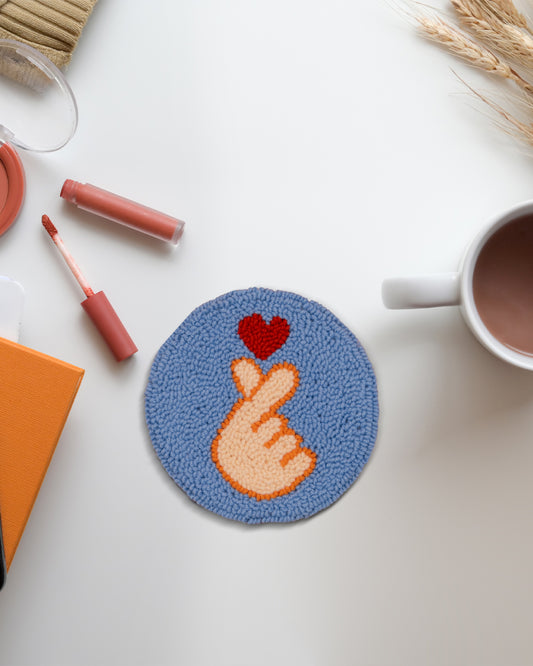 Round Korean heart punch needle coaster with finger heart design by Kozi Crafts