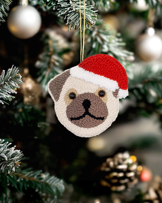 Handmade punch needle bulldog ornament wearing a Santa hat hanging on a Christmas tree.