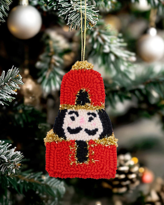 Handmade punch needle nutcracker ornament hanging on a Christmas tree.