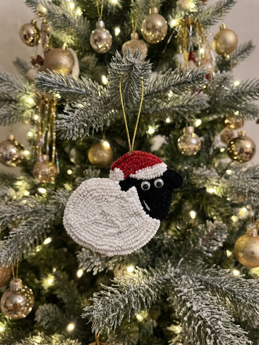 A handmade beaded Christmas ornament shaped like a sheep wearing a Santa hat, hanging on a decorated Christmas tree with gold ornaments and warm lights.
