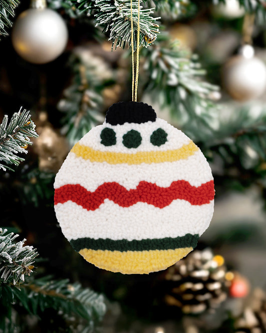 Round punch needle Christmas bauble ornament with festive stripes and dots hanging on a Christmas tree.