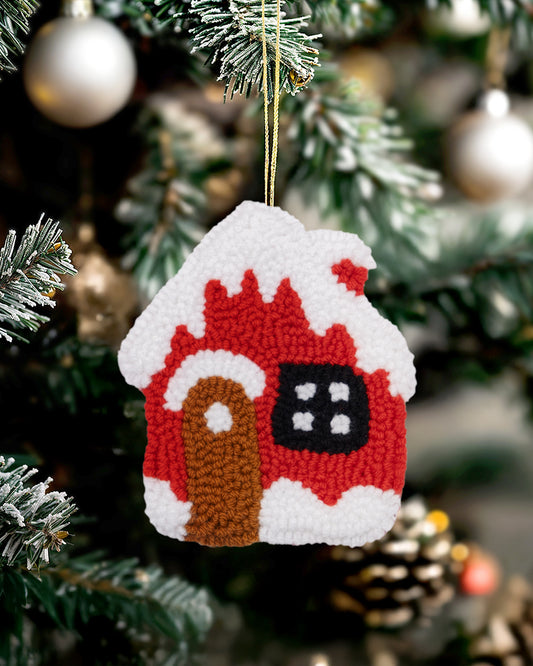 Handmade punch needle gingerbread house ornament hanging on a Christmas tree.