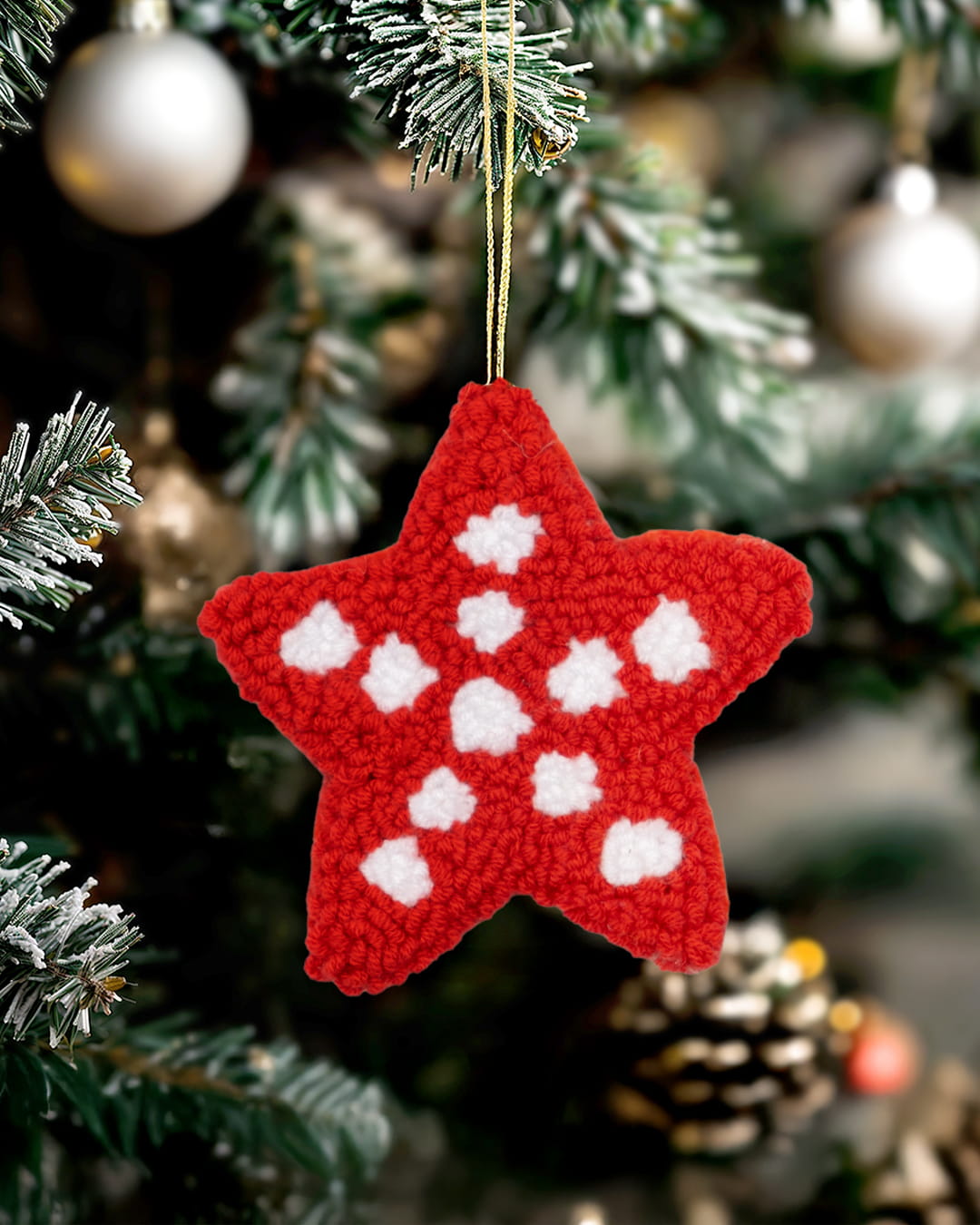 Handmade punch needle star ornament hanging on a decorated Christmas tree-red