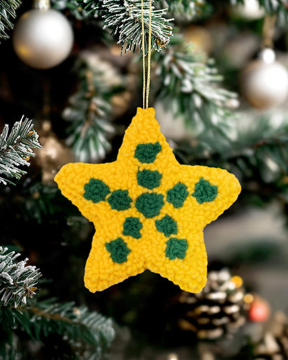 Yellow star-shaped ornament with green dots hanging on a Christmas tree.