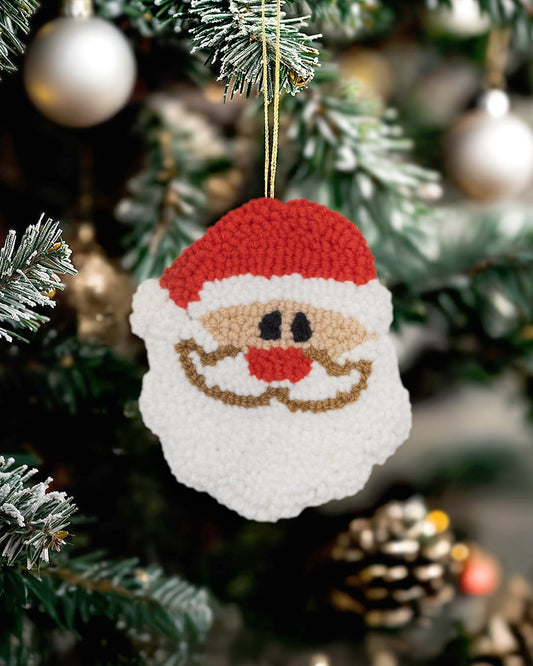 Handmade punch needle Santa face ornament hanging on a decorated Christmas tree.