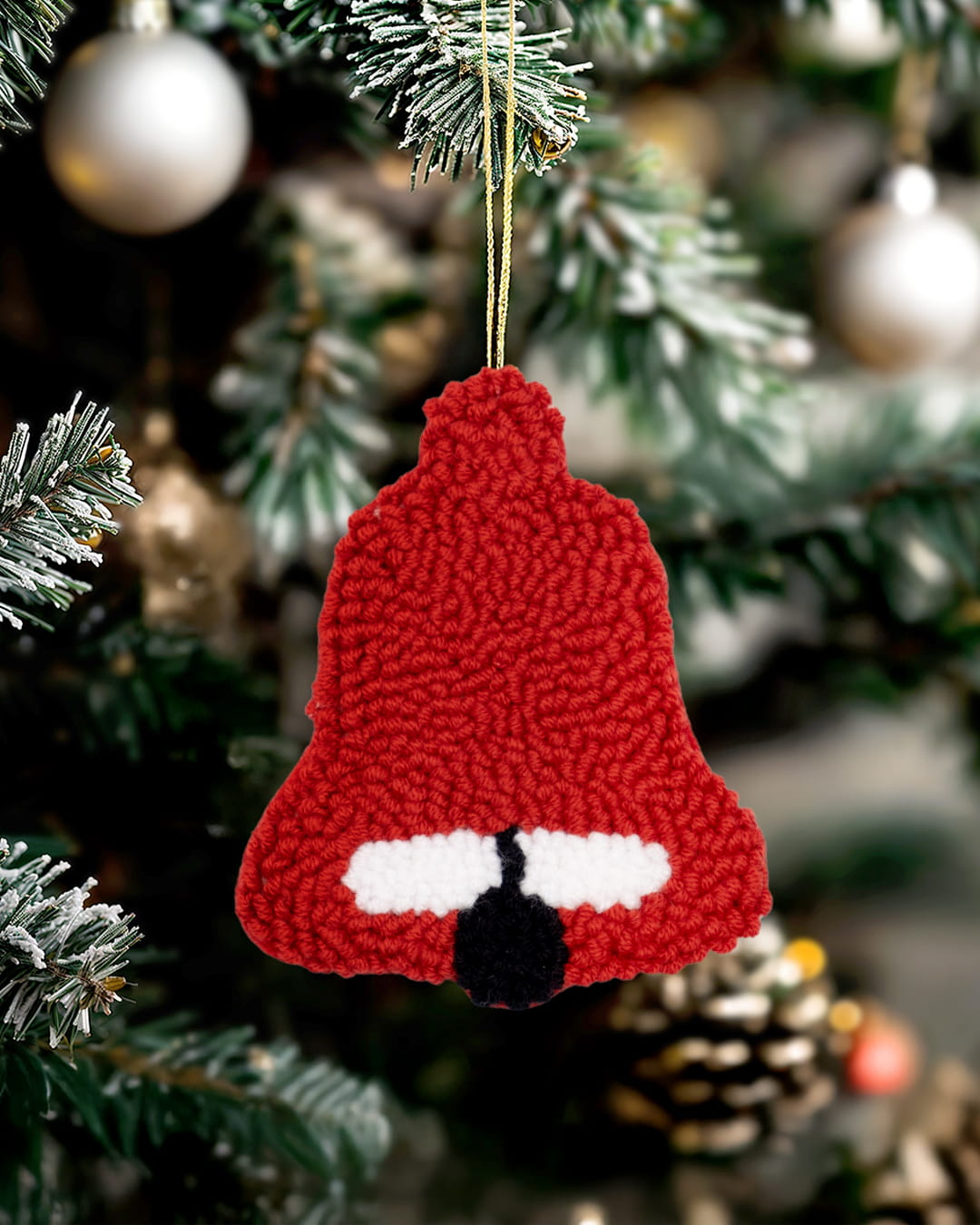 Punch needle Christmas bell ornament by Kozi Crafts styled on a festive holiday tree.